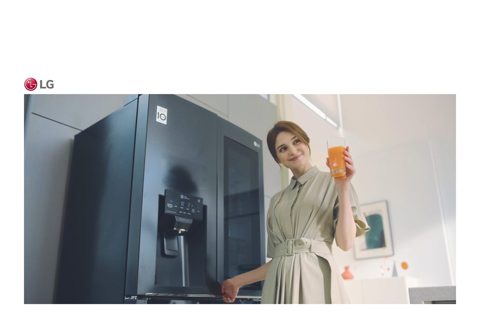 صورة يظهر بها امرأة تقف أمام الثلاجة تحمل كأسًا من العصير وتبتسم أثناء غلق الباب.