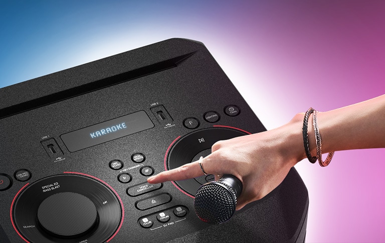 A hand holding a microphone tries to press the Voice canceller button on the top of LG XBOOM.