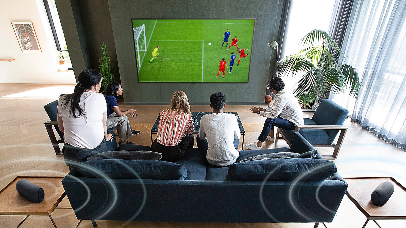 5 people gathered in front of a wall mounted flatscreen TV watching a football game.