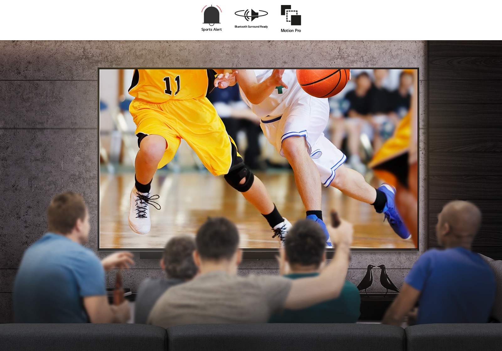 Rear view of a group of men sat in front of a large wall-mounted TV. The screen shows basketball players.