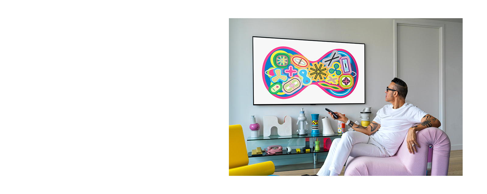 An industrial designer, Karim Rashid sitting on a sofa is watching a TV displaying a painting. 